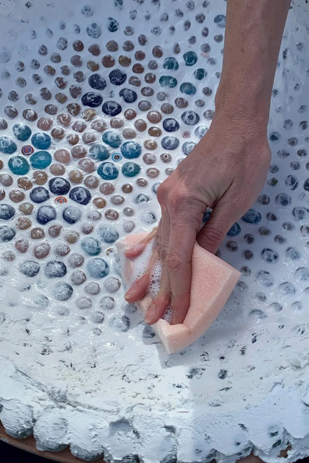 Step 5. A sponge and water will wash the excess grout off your mosaic bird bath.