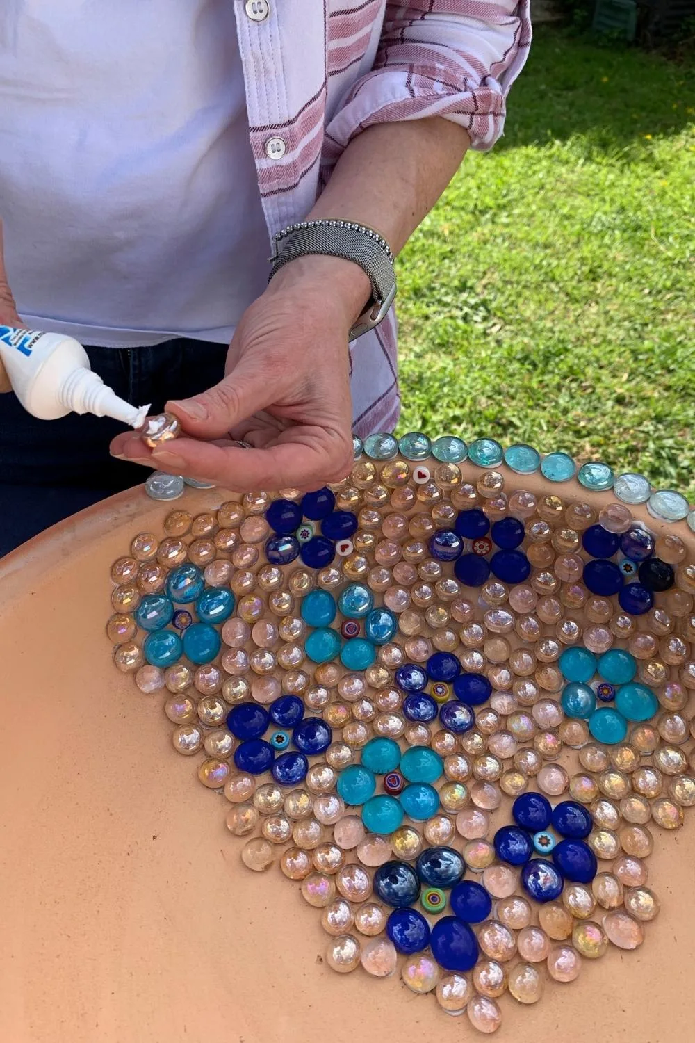 Step 2 involves applying mosaic glue to the back of each pebble to create the design.
