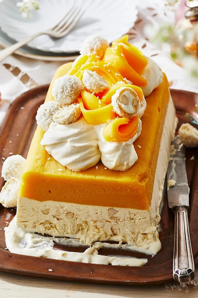 Mango ice-cream cake in rectangular shape with cream ontop