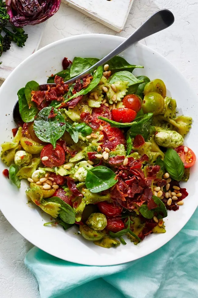 Pasta salad with pesto cooked prosciutto and cherry tomatoes