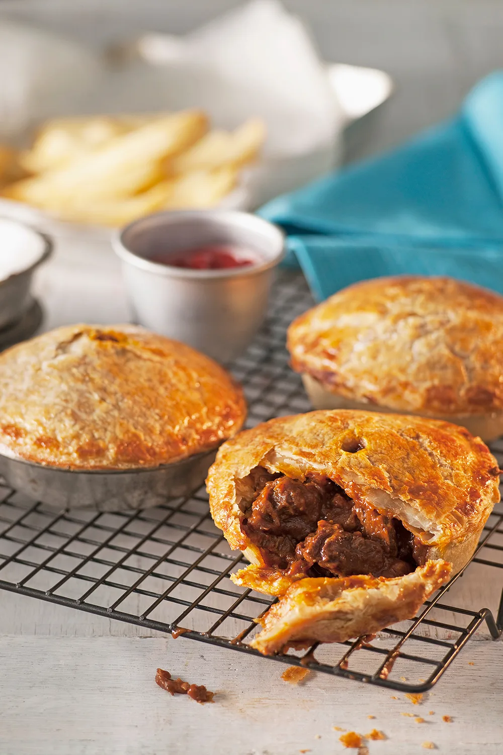 Aussie meat pie on cooling rack with bite taken out of it