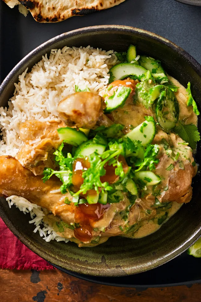 curried chicken drumsticks in bowl with fresh herbs sprinkled on top