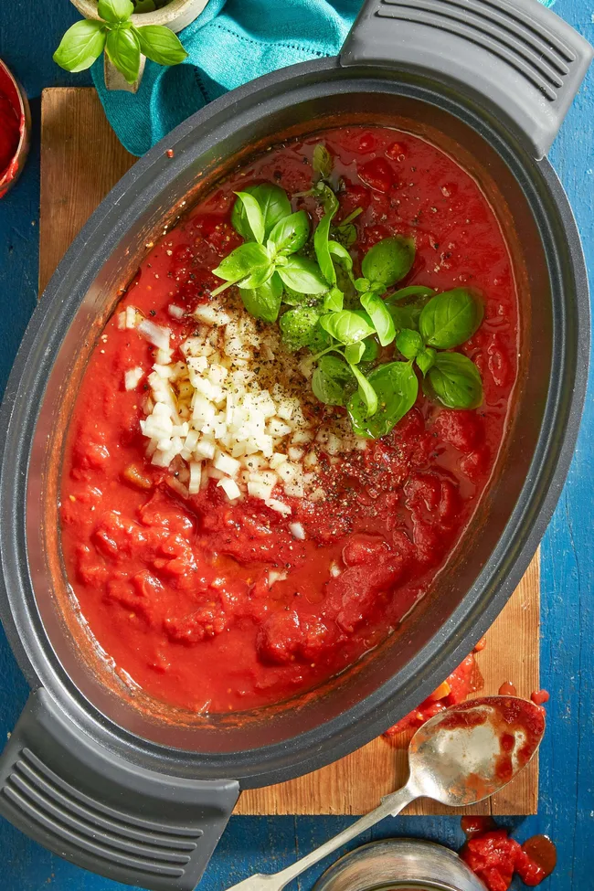 Slow-cooked tomato Napoletana sauce with basil and diced onion on top still in the slow cooker