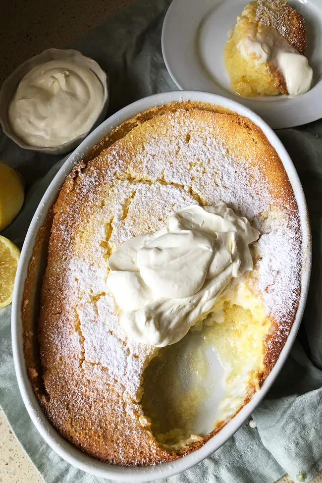 lemon dessert recipes lemon delicious pudding with scoop taken out and cream on top
