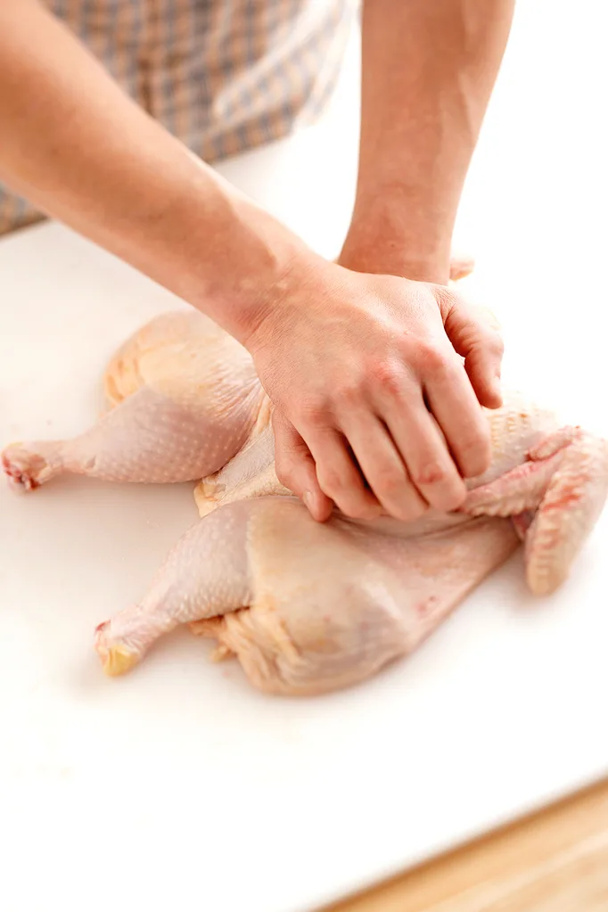 Spatchcocking a chicken breaking the breast bone with two hands