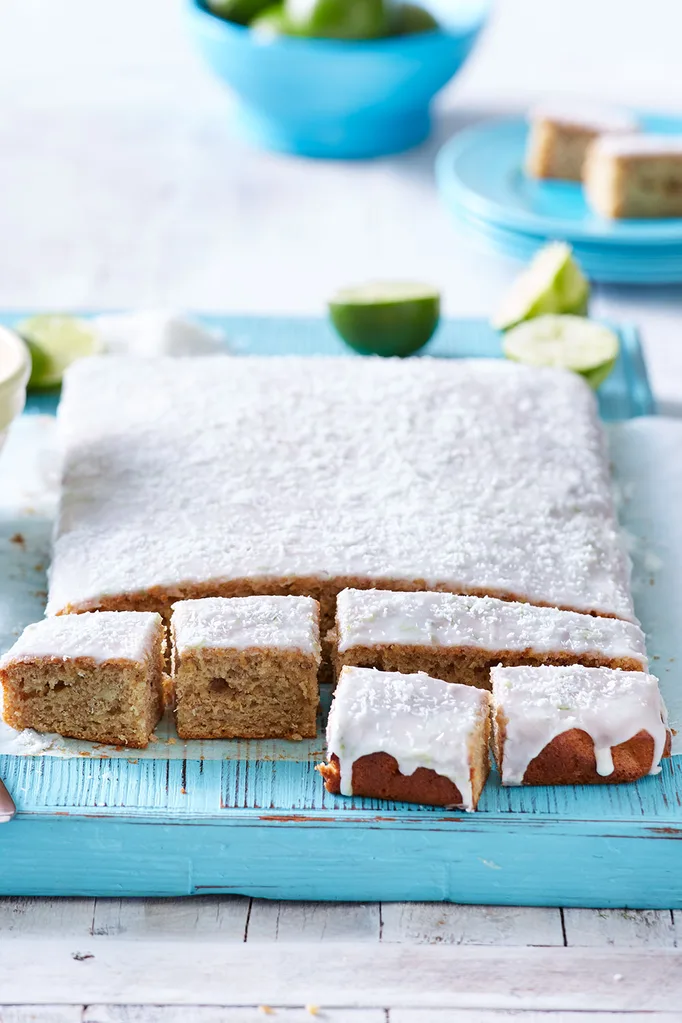 banana bread loaf with icing and desicated coconut sprinkled on top on blue tablecloth