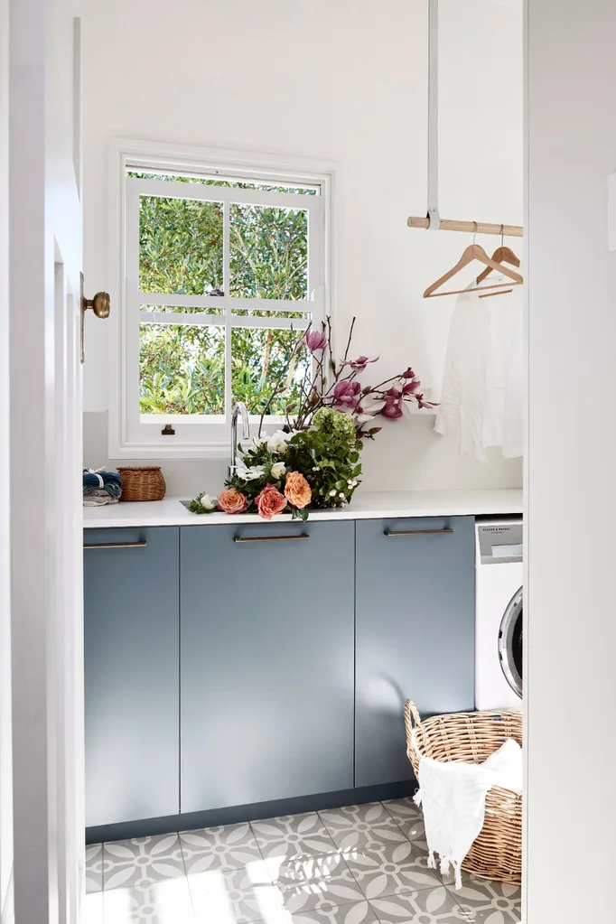 laundry with blue grey cabinets and laundry hamper made of wicker in the corner