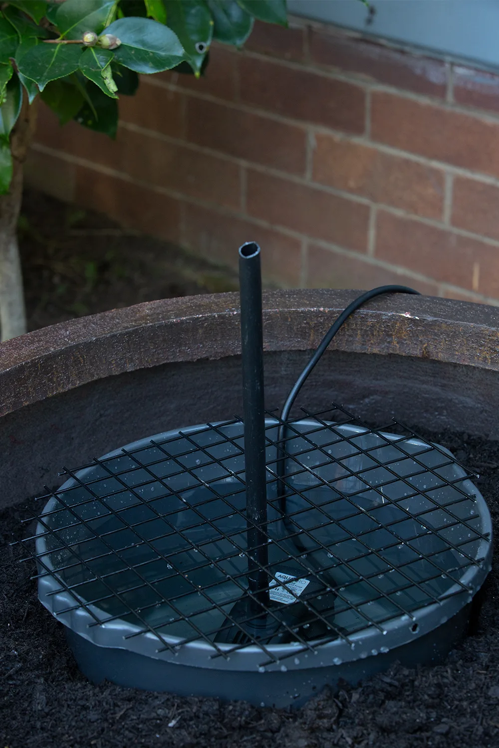 water feature being set up with connected pipe and metal grate on top