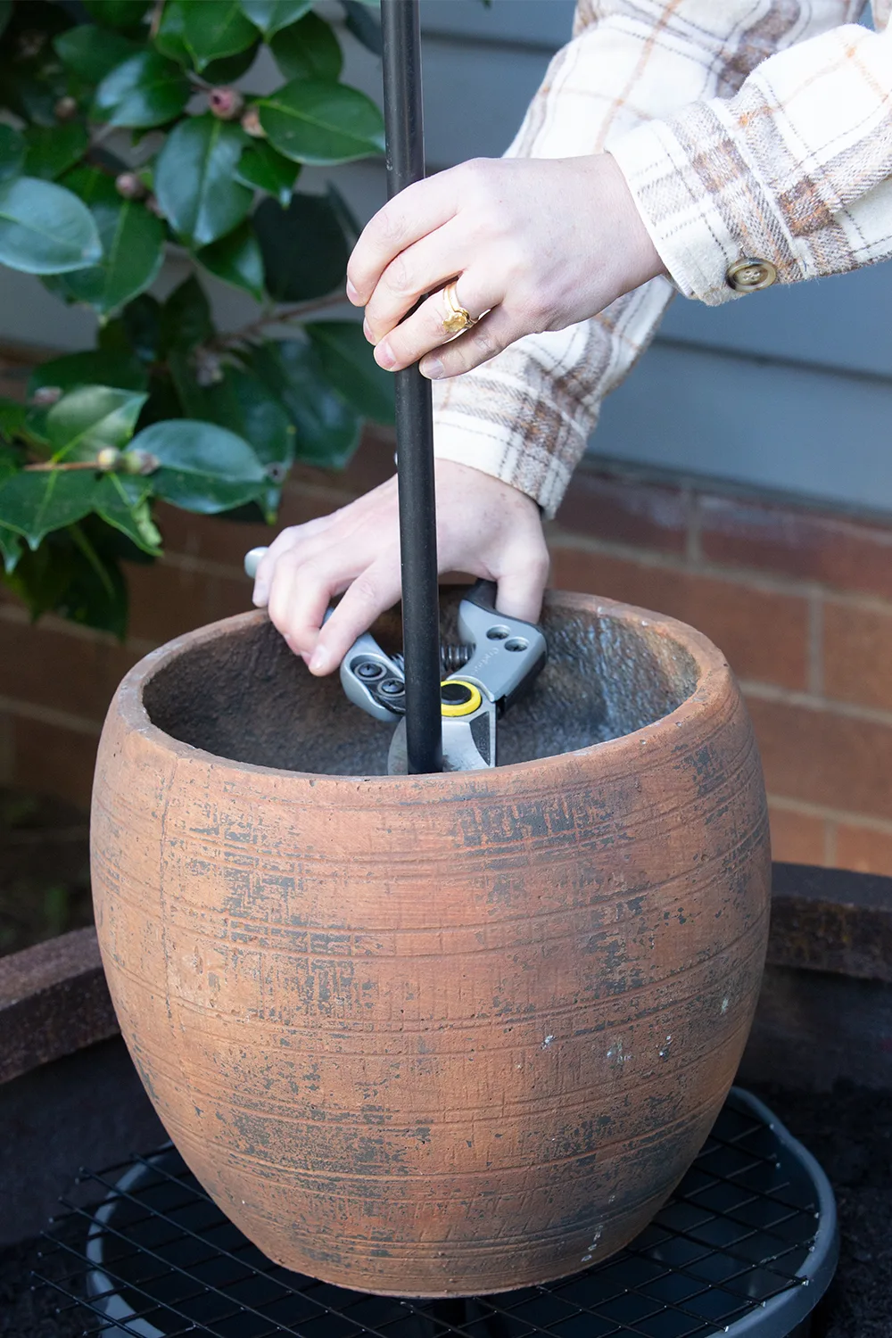 hand cutting down the pipe in multi level water feature pot