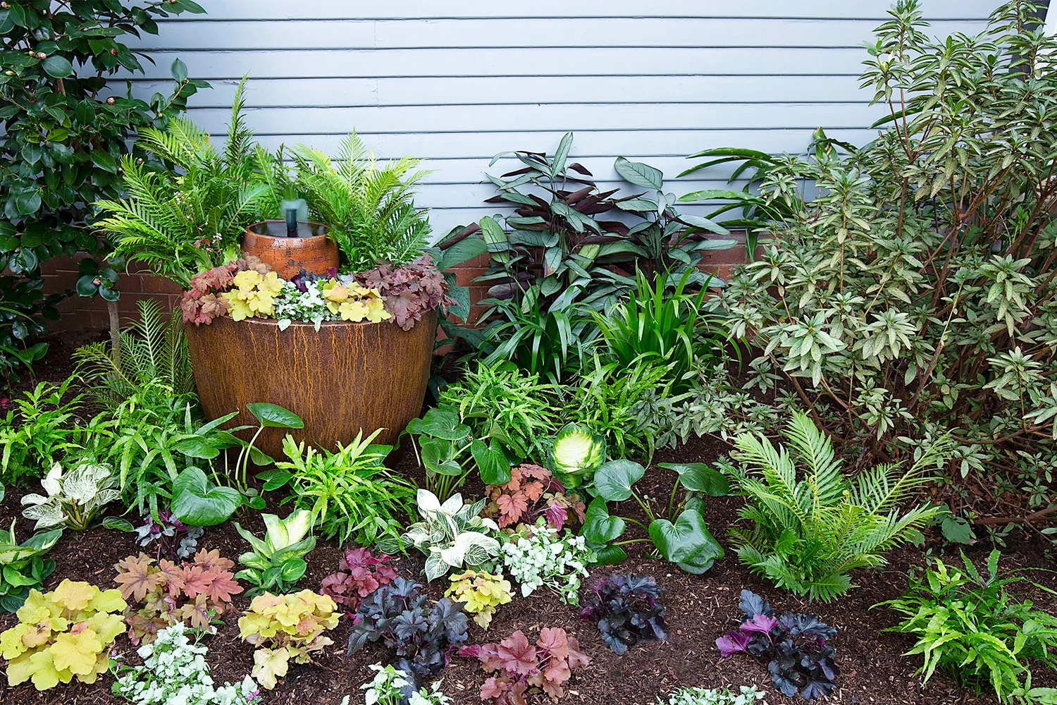 shady ferns surrounding pot with water fountain in it