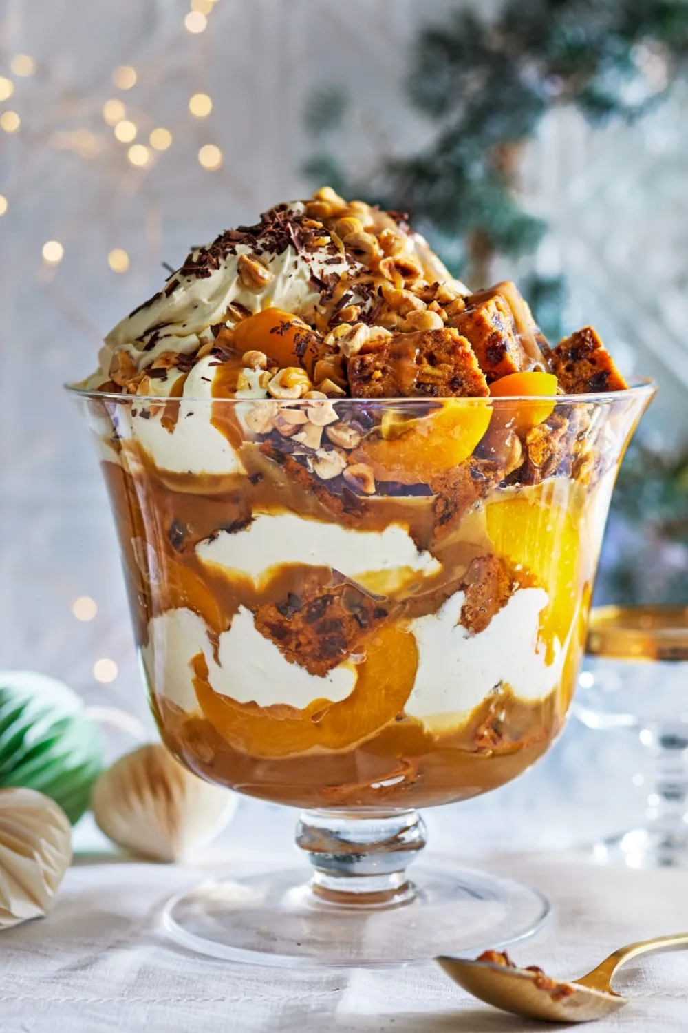 peach trifle in glass trifle container with nuts sprinkled on top