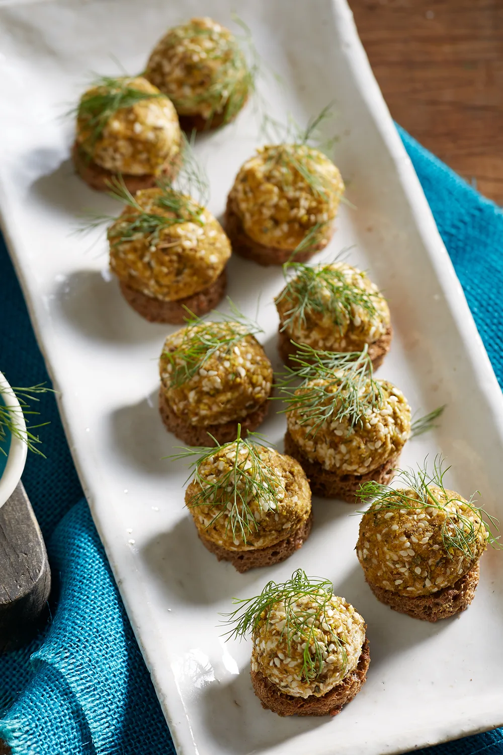 Olive and goat's cheese bites small balls of food with piece of dill placed on top