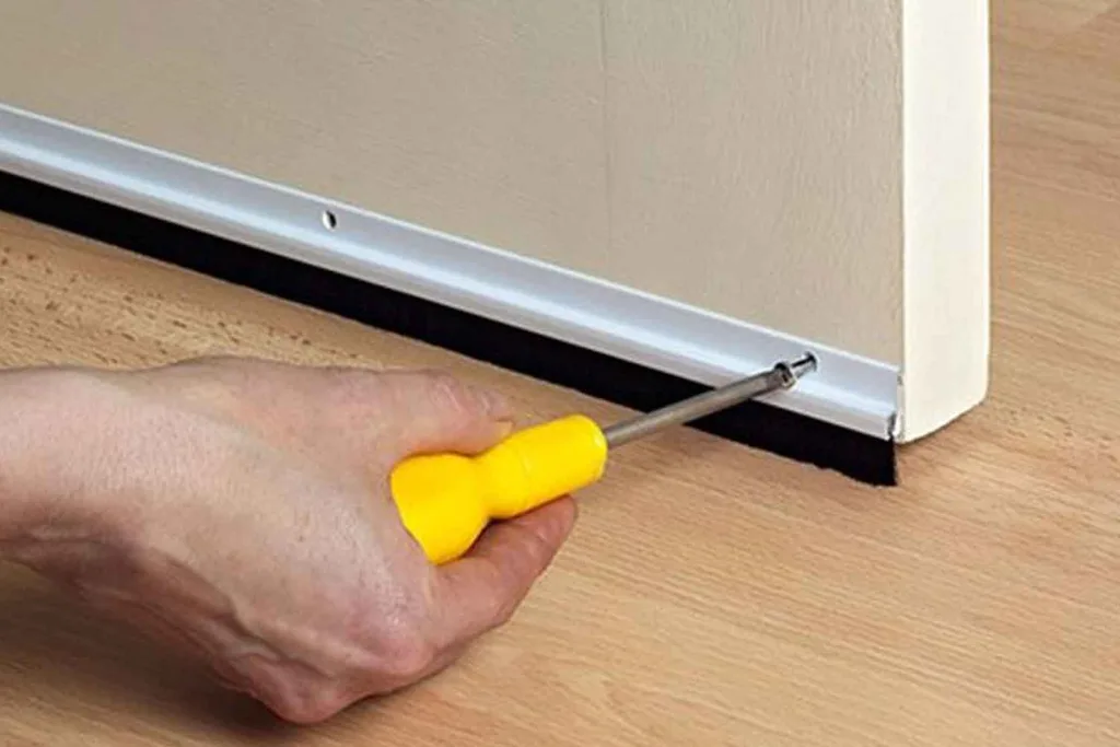 installing a darught stopped to a door with a screw driver