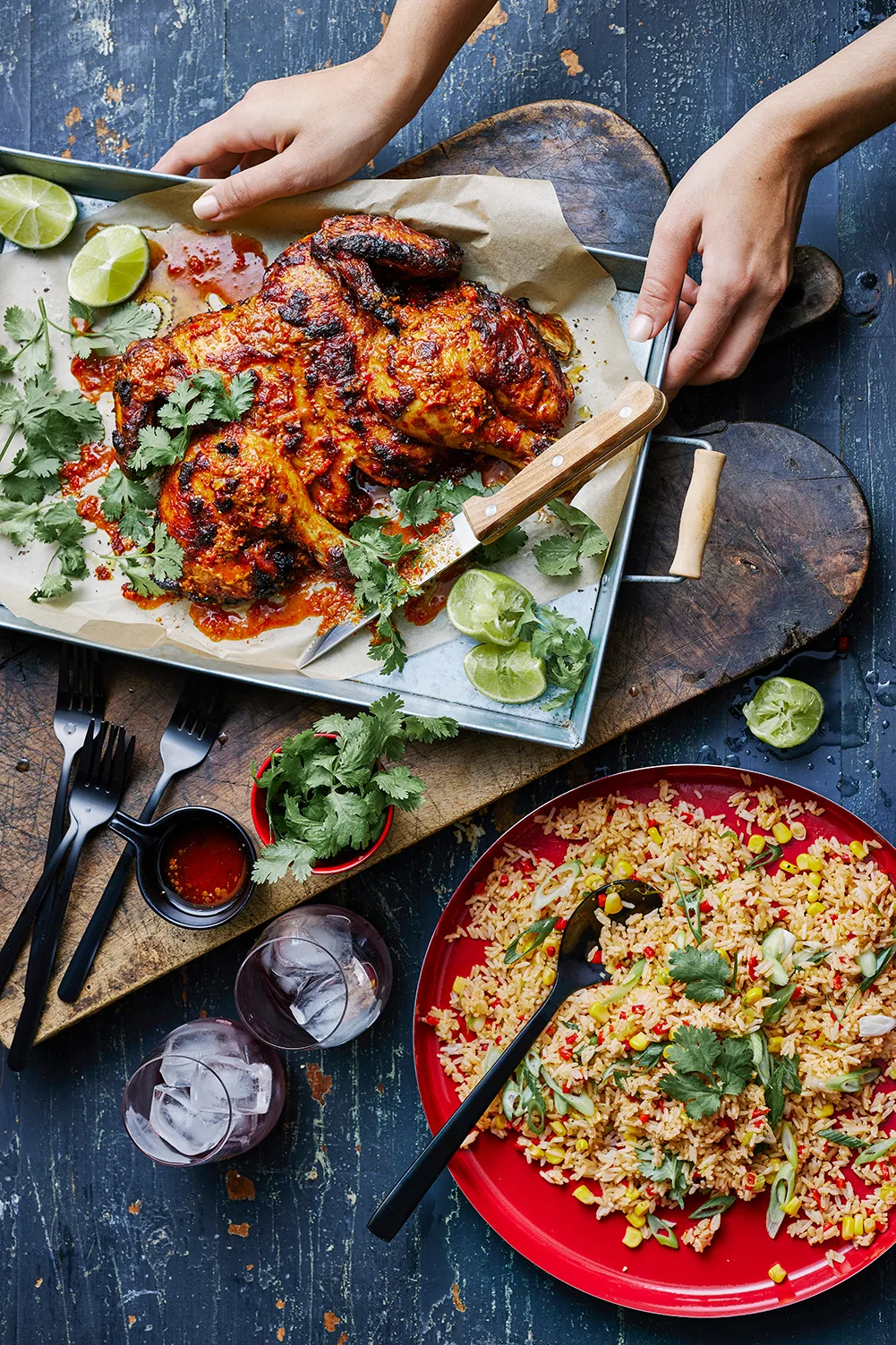 Portuguese chicken with coriander lime and knife on baking tray with fried rice in bowl next to it