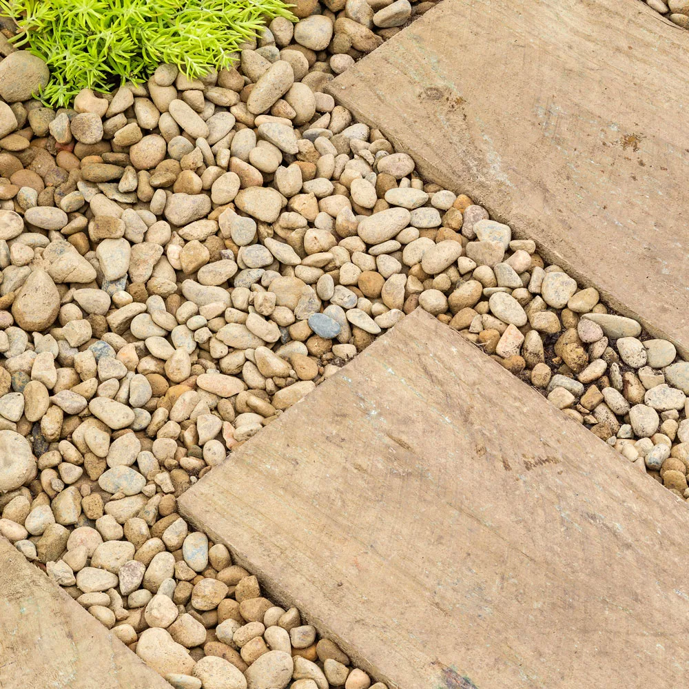 Decorative pebbles placed around wooden sleepers add texture to garden features.
