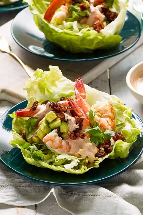 prawn cocktail in lettuce cups with avocado and mayo sauce on top