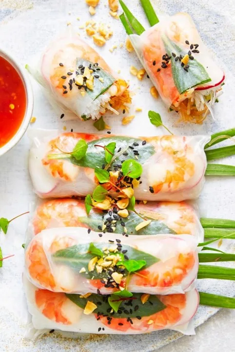 rice paper rolls layed out in a line with black sesame seed on top
