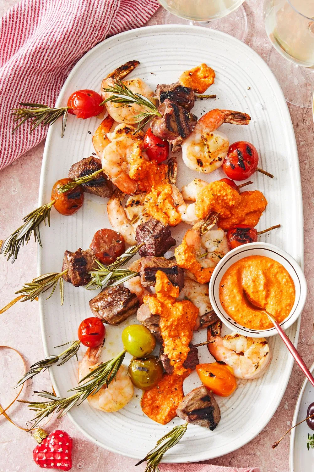 surf-and-turf on skewers with rosemary sticking out of the top on white oval platter