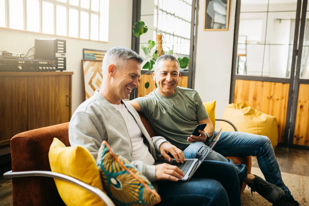 two men chatting and using a laptop