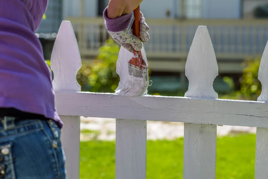 a person painting a white picket fence