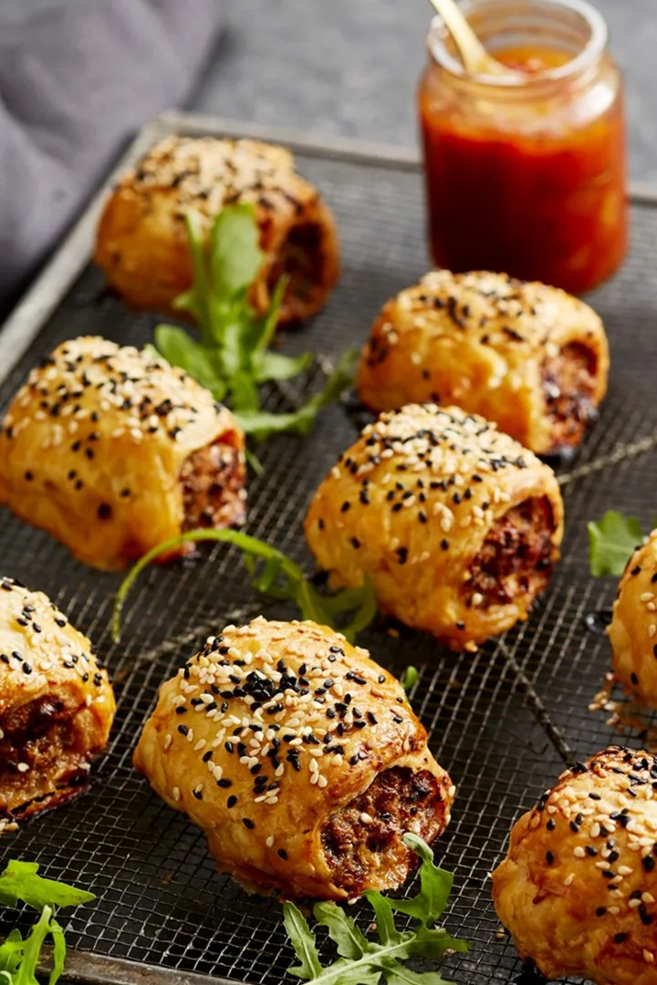 pork mince sausage rolls with sage on a baking tray
