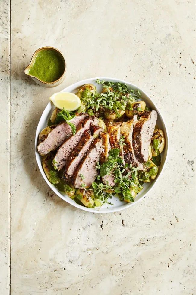 bbq lamb and potato salad in bowl with leafy greens