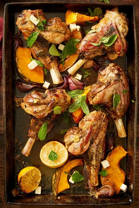 slow roasted greek lamb shanks sitting on a baking tray after being in the oven