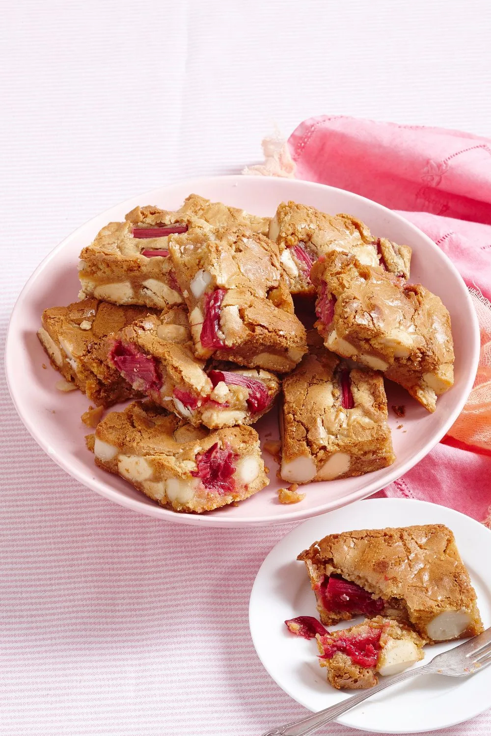 blondies with macadamia and rhubarb pieces in them on pink plate