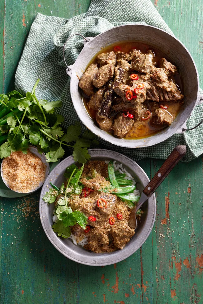 beef rendang in bowl with fresh herbs on top