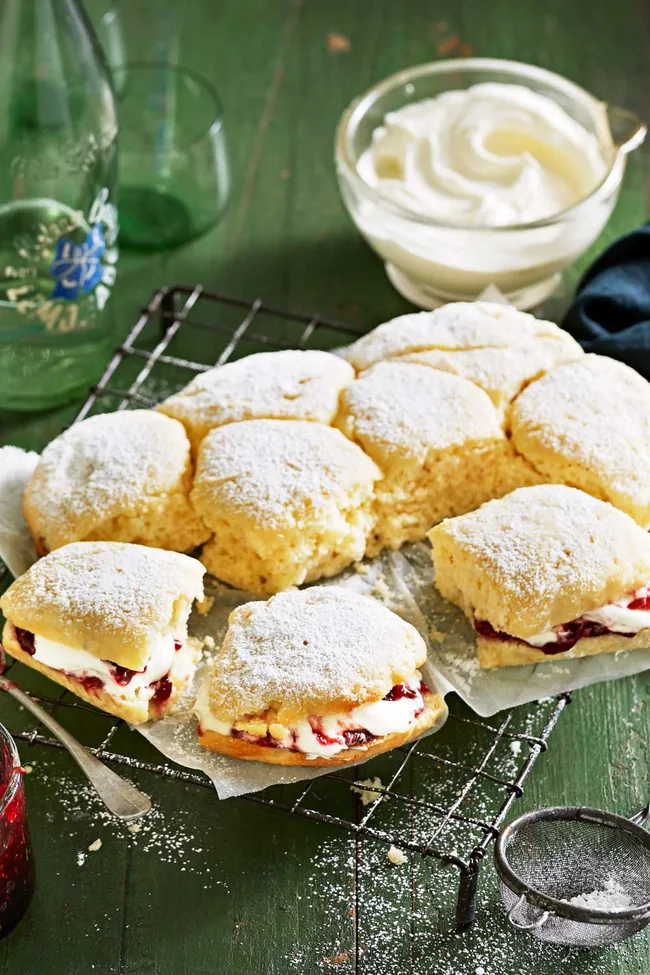slow cooker scones on baking tray filled with jam and cream