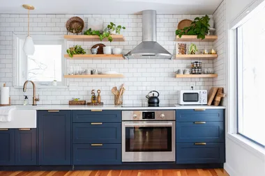 A kitchen with blue cabinets and white subway tiles.