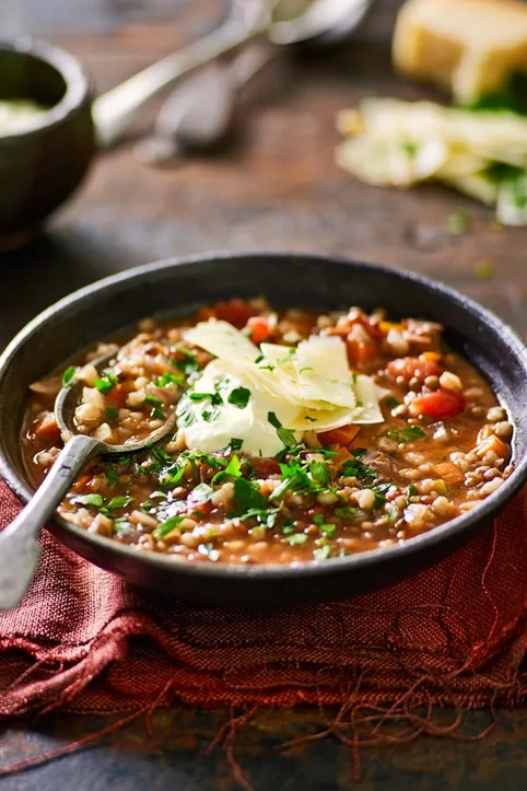 vegetable and lentil soup with spoon sticking out of bowl