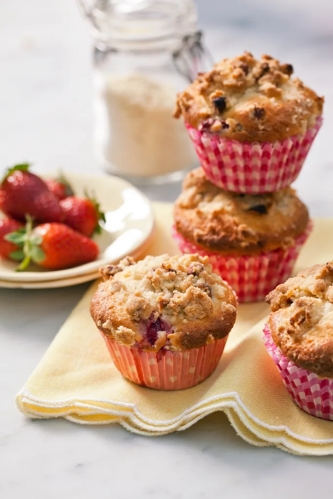 strawberry and almond muffins with plate of strawberries in background