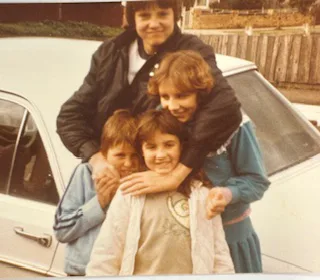 four children stood in front of a white car