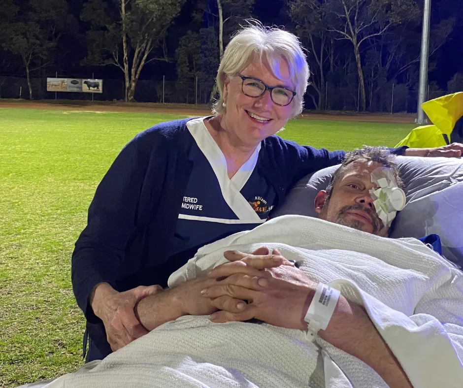 Nurse next to man on a stretcher outside at night in a field