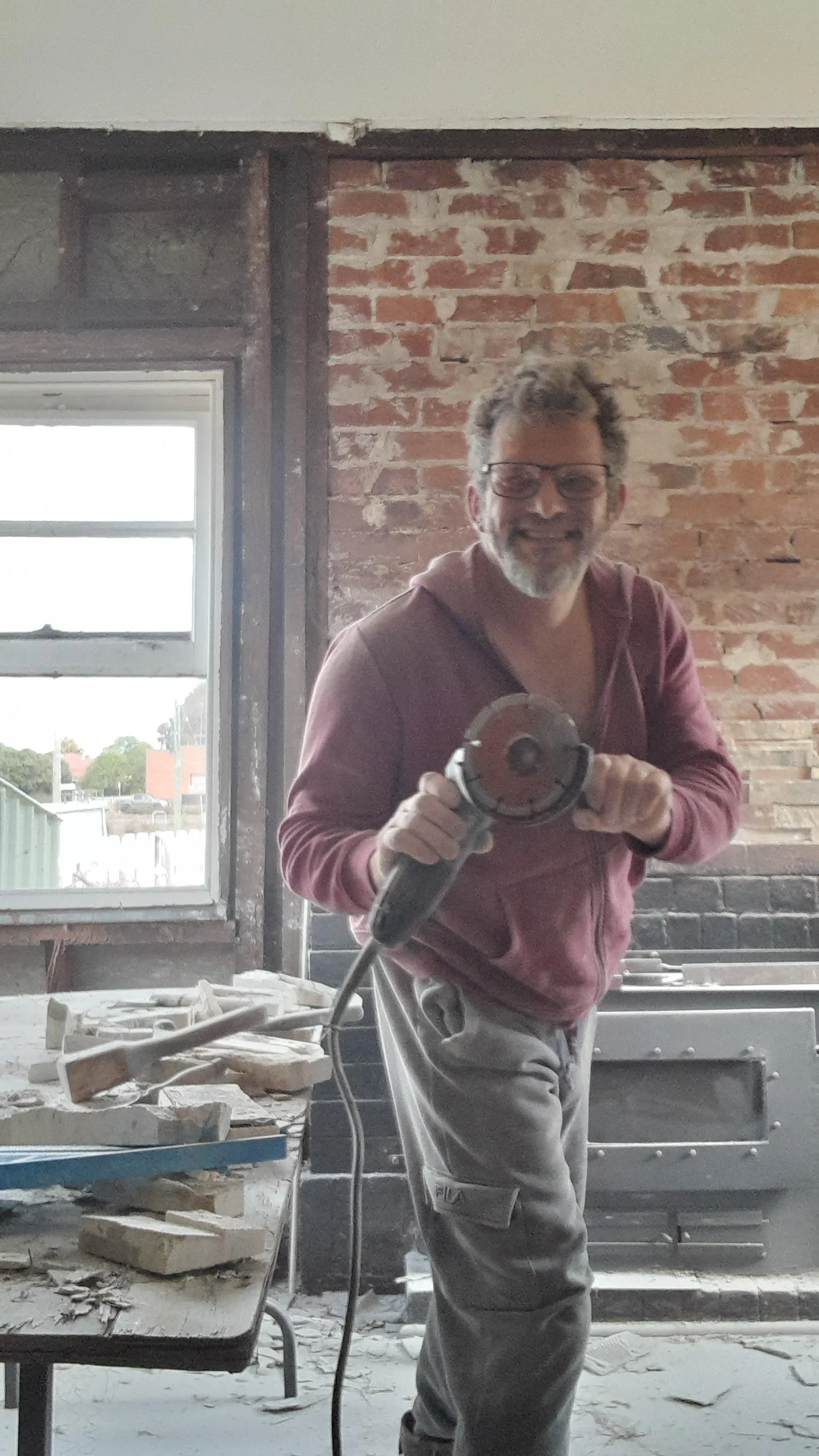 Man with a power tool in a brick-walled interior room