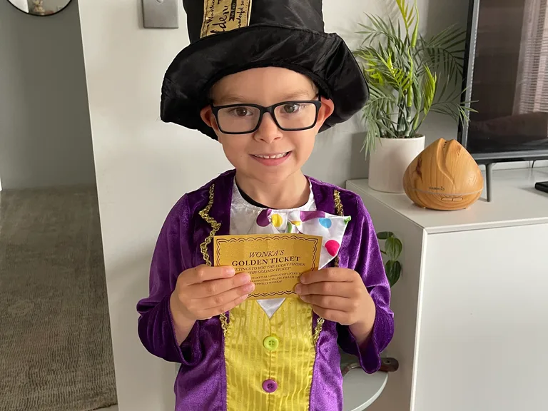 Boy dressed as Willy Wonka holding a golden ticket