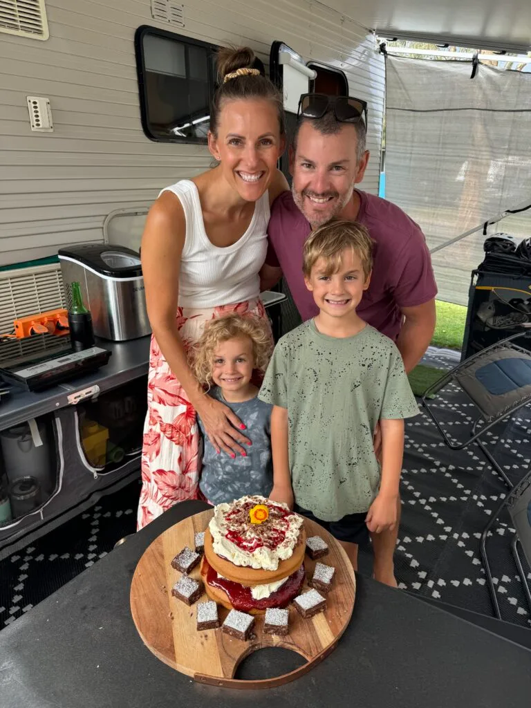 Family photo capturing parents and two young boys cutting a birthday cake