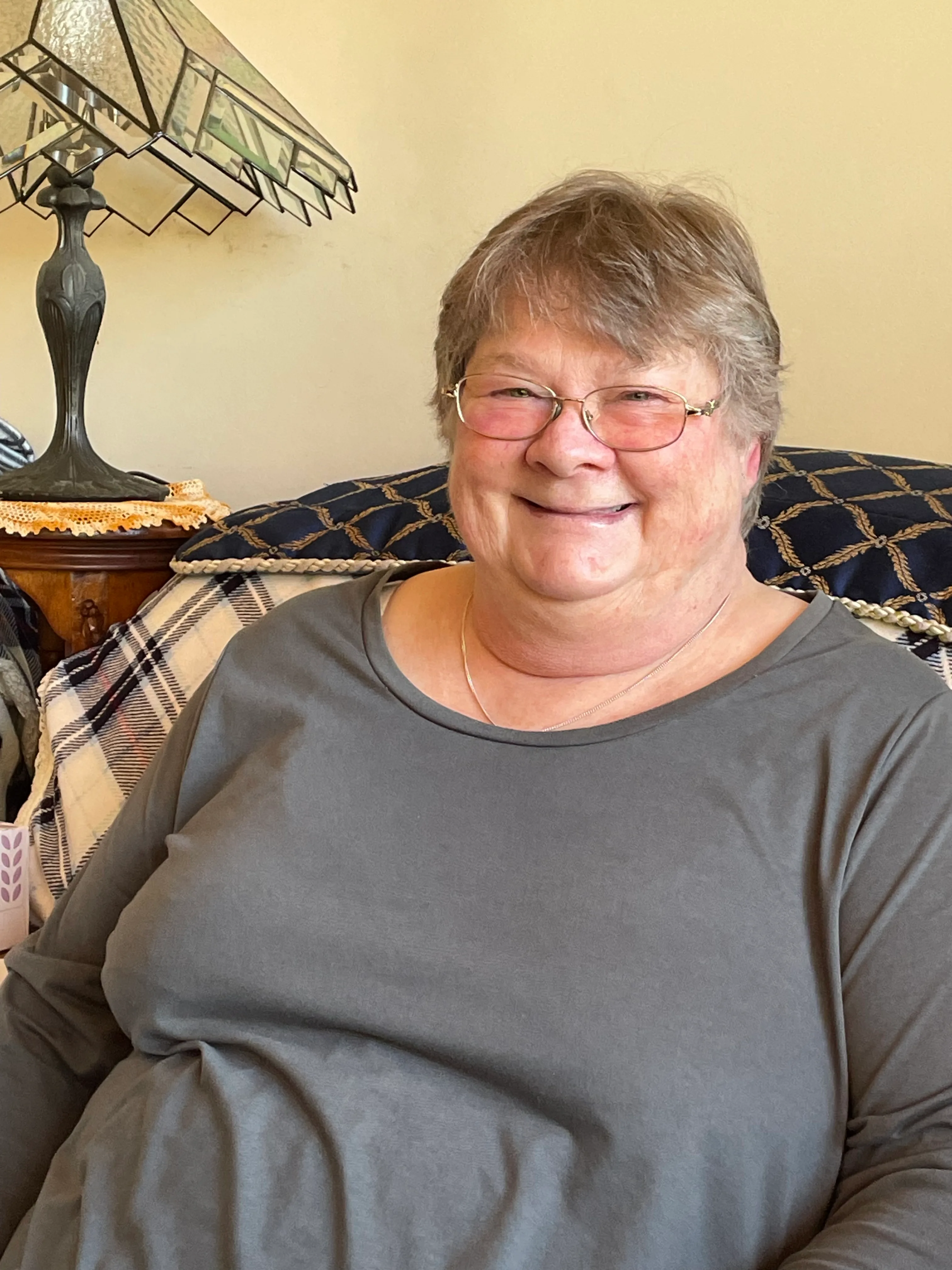 Photo of woman/carer sitting in lounge chair and smiling