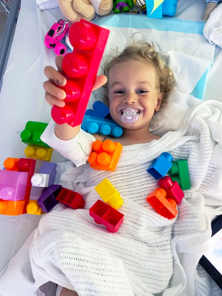 Photo of young boy recovering in hospital and playing with colours blocks