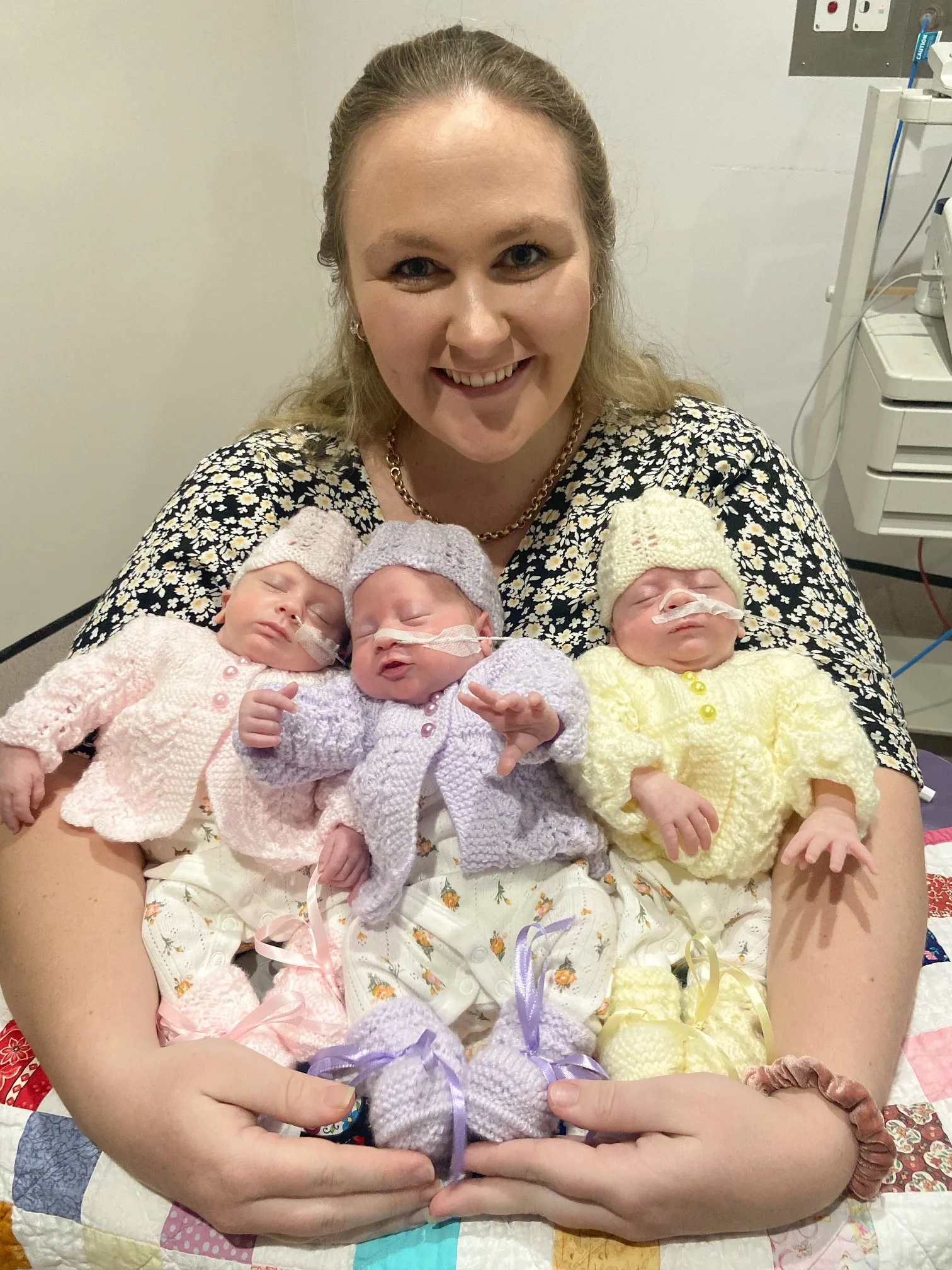 Image of mum holding newborn triplet girls in hospital
