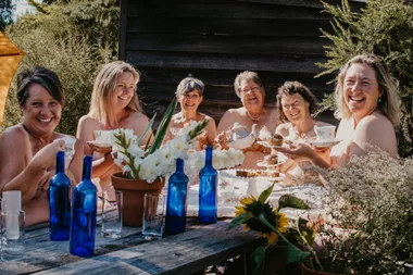 Image of women sitting around a table in the nude