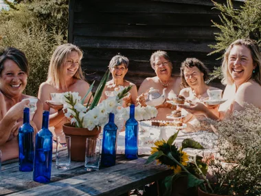 Image of women sitting around a table in the nude