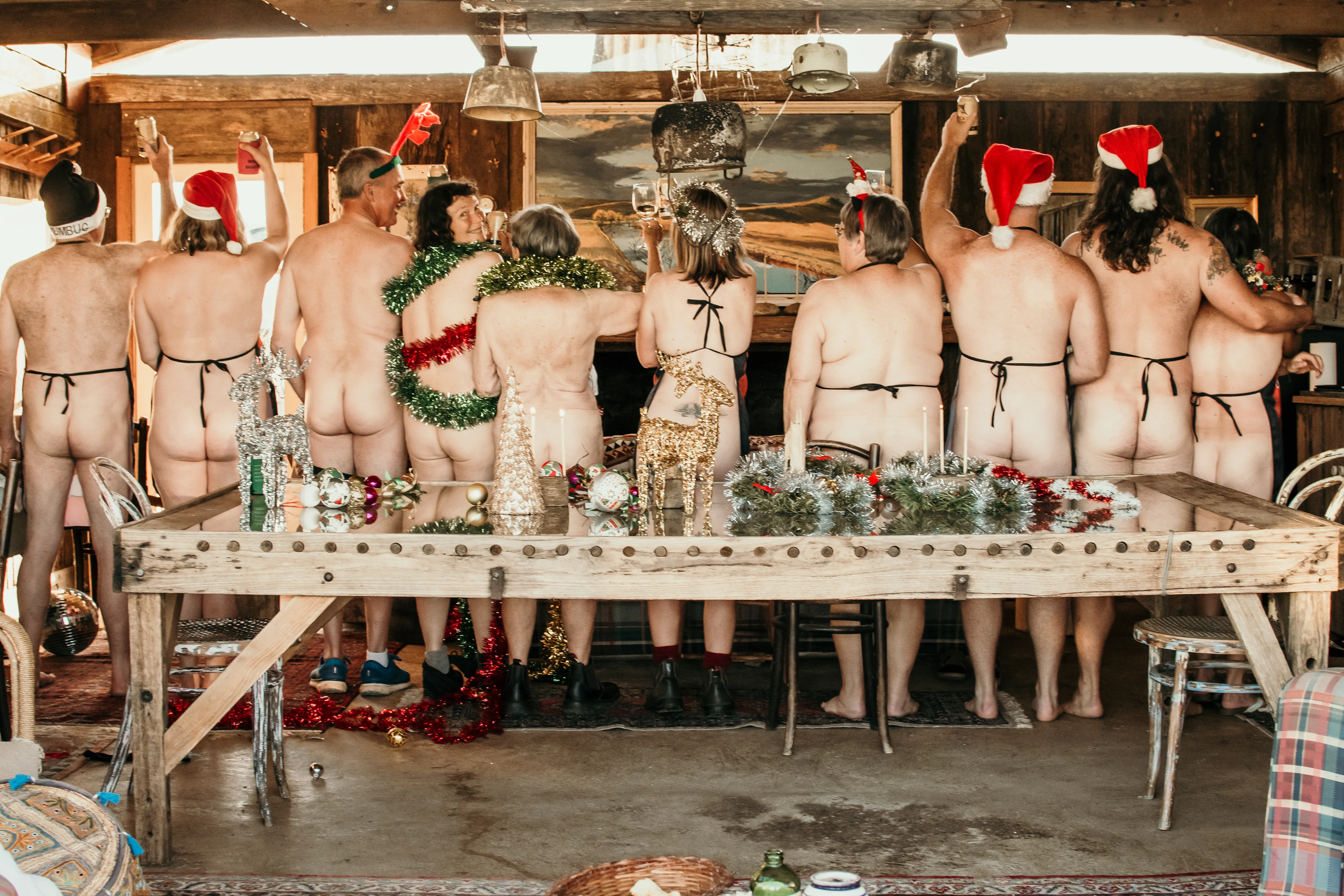 Image of men and women standing in the nude wearing santa hats