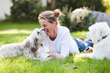 woman in white with two dogs laying on the grass