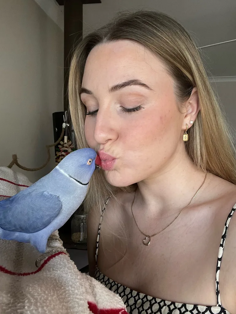 Image of girl kissing blue indian ringneck parrot