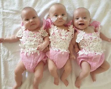 Image of newborn triplet girls wearing matching onesies