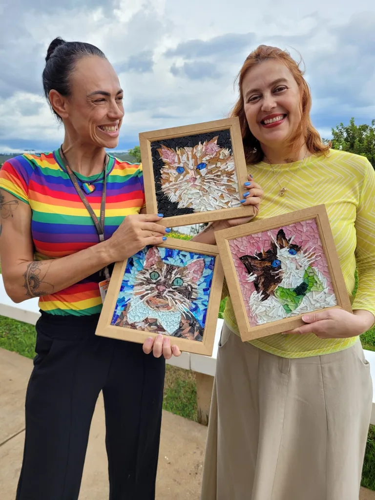 Image of two women holding paintings of cats