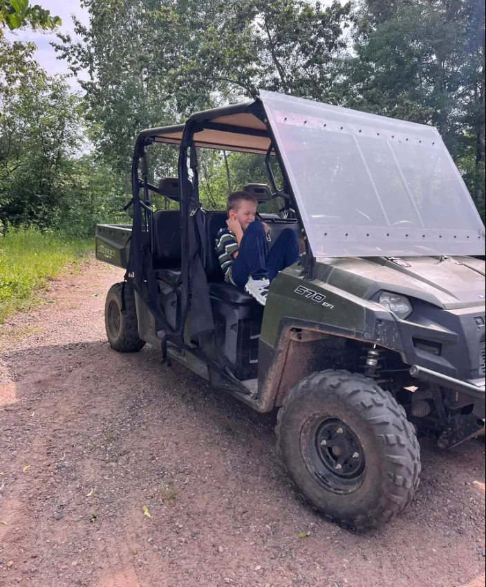 A child sitting in the passenger seat of an All Terrain Vehicle (ATV).