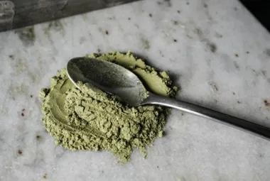 Green powder on a spoon on a chopping board